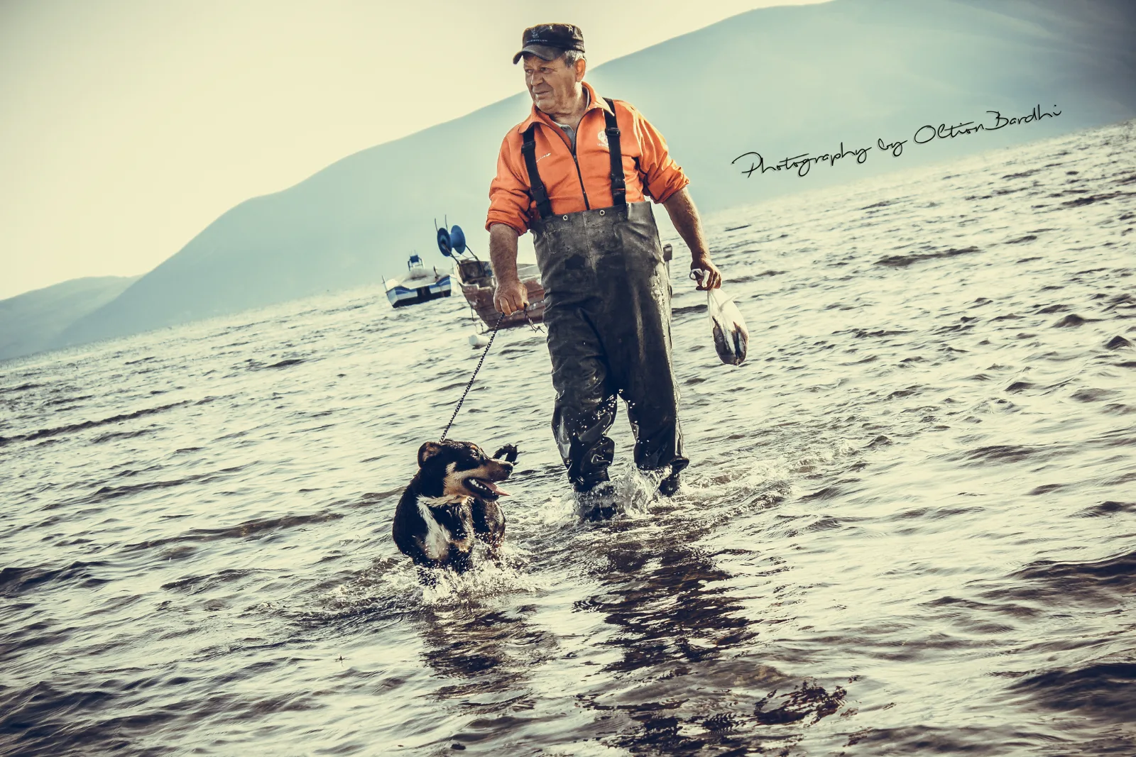 Angler mit Hund watet ins Wasser