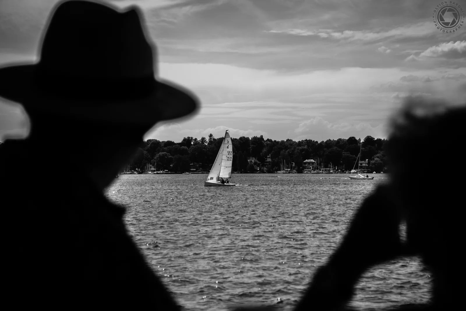 Silhouetten beobachten ein Segelboot auf dem See